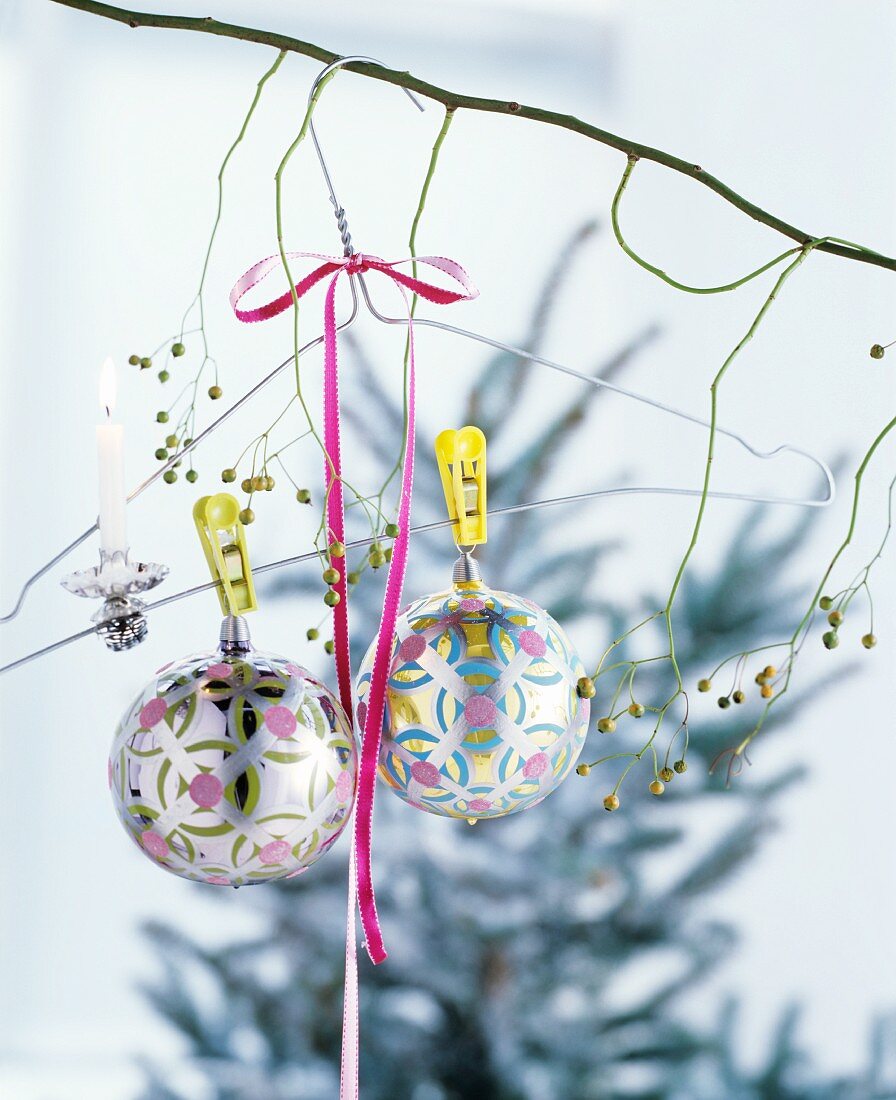 Christmas-tree candle clipped to wire coat hanger and baubles hanging from bare branch