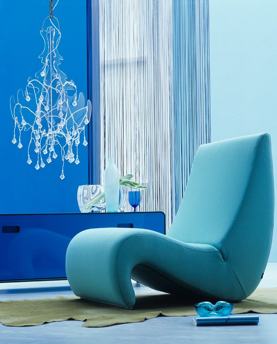 Organisch geformter Sessel in blauem Raum mit Kronleuchter