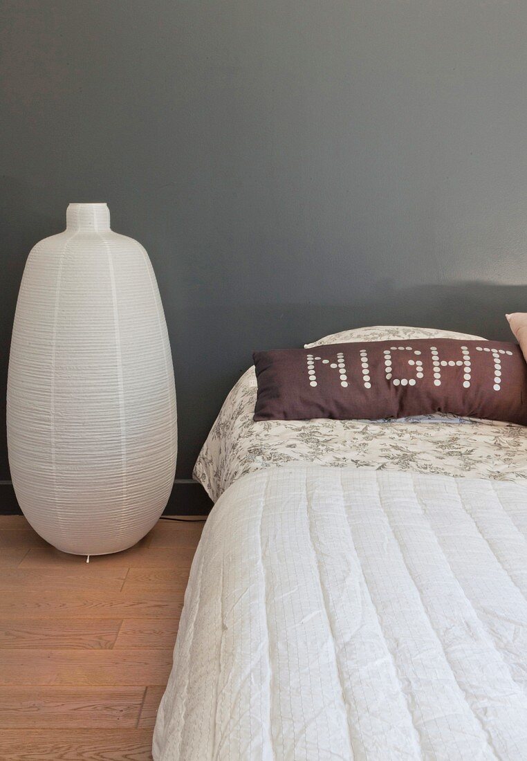 Paper lantern on floor next to bed and pillow with motto 'NIGHT' on bed
