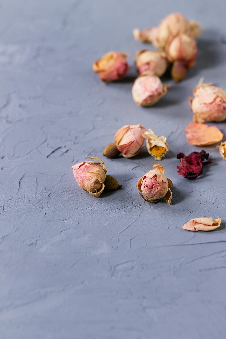 Dry rosebuds and chamomile flowers on grey textured surface