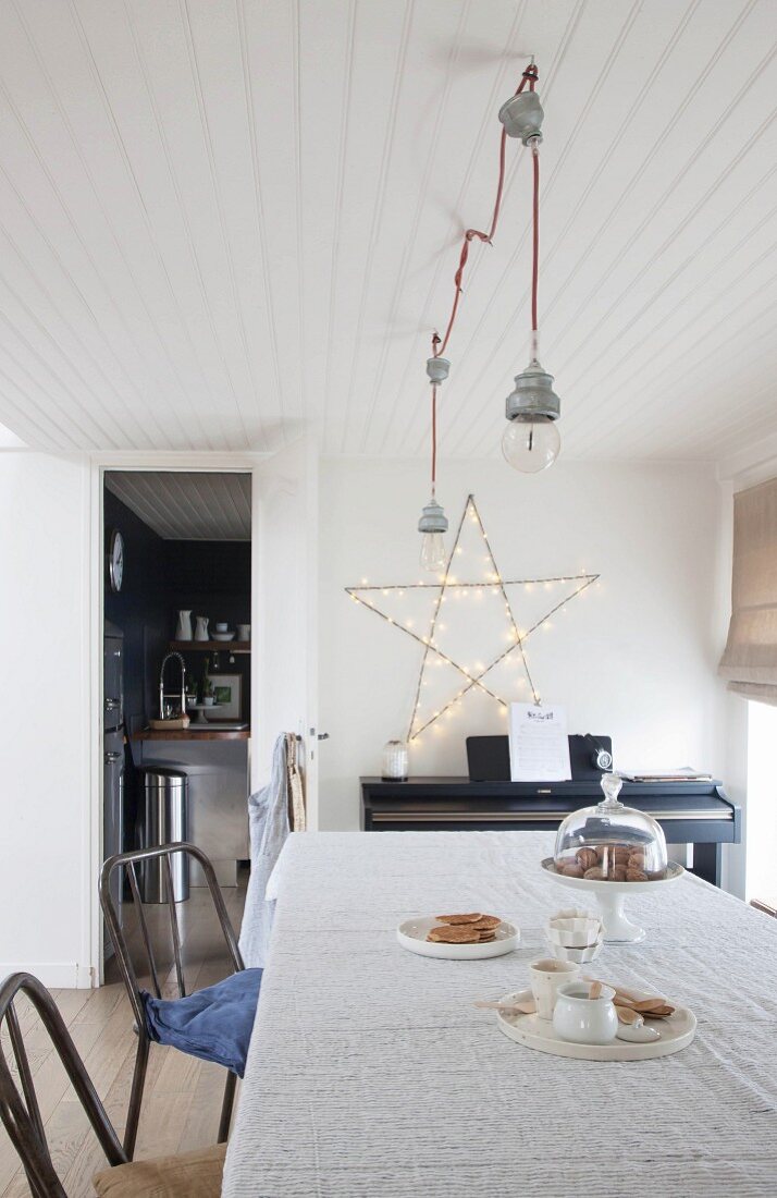 Large fairy-light star on wall in simple dining room