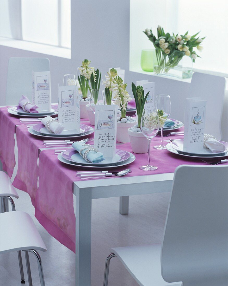 Festlich gedeckter Tisch mit weißen Hyazinthen, Menükarten und mauvefarbenen Tischläufern