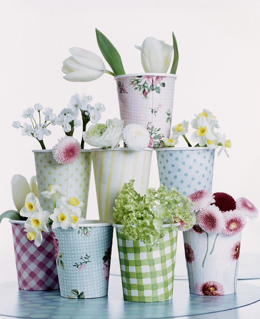 Verschiedene Pappbecher mit unterschiedlichen Frühlingsblüten dekoriert und gestapelt