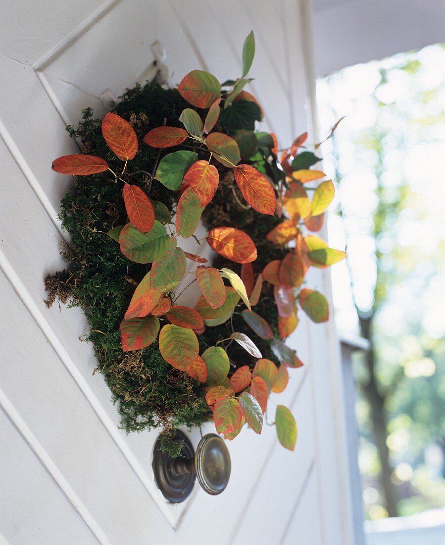 Autumnal moss door wreath decorated with colourful leaves
