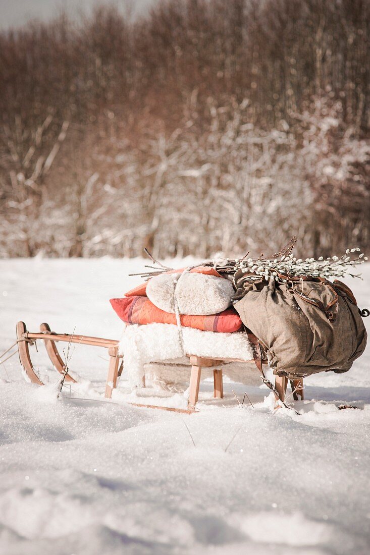 Mit Decken und Rucksack bepackter Schlitten in Winterlandschaft