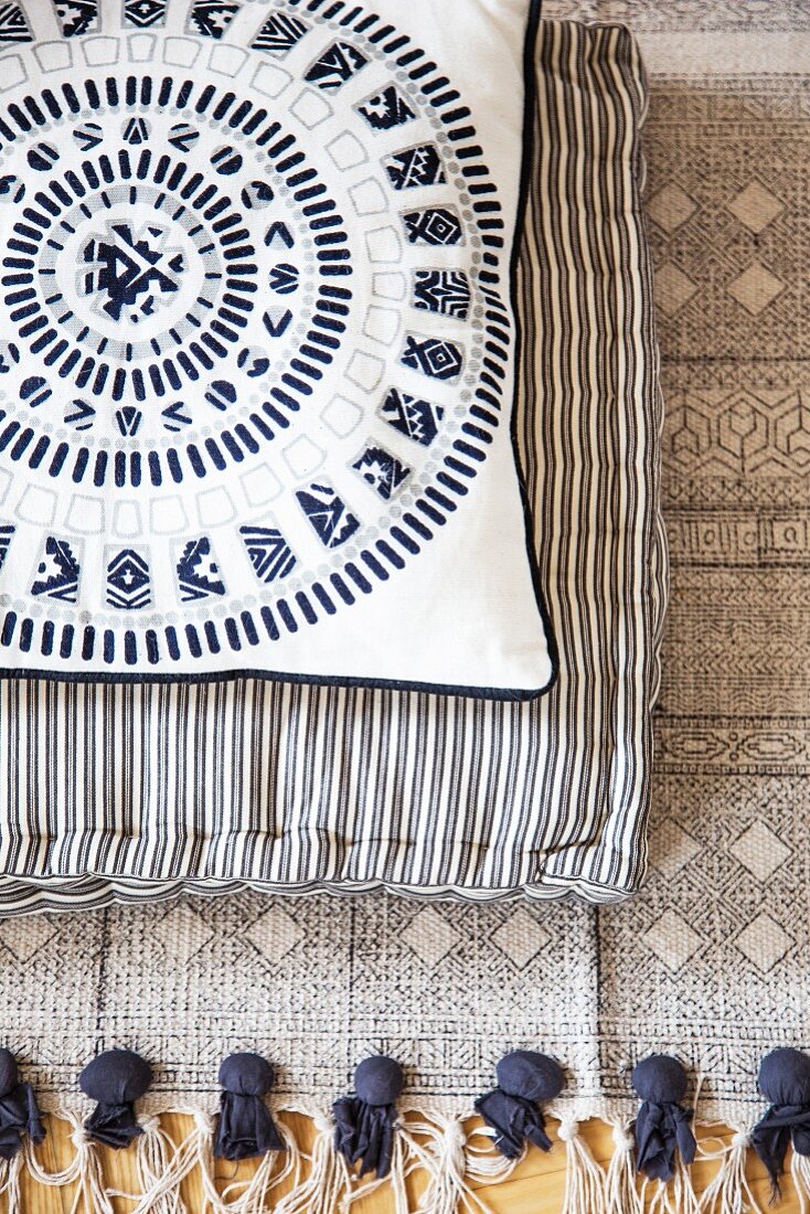 Two cushions with different patterns on ethnic fringed rug