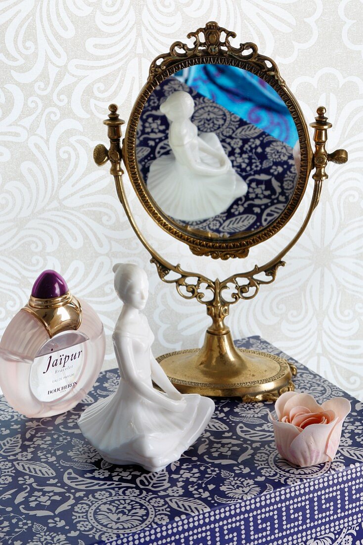 Feminines Stillleben mit Spiegel, Porzellanfigur und Parfum
