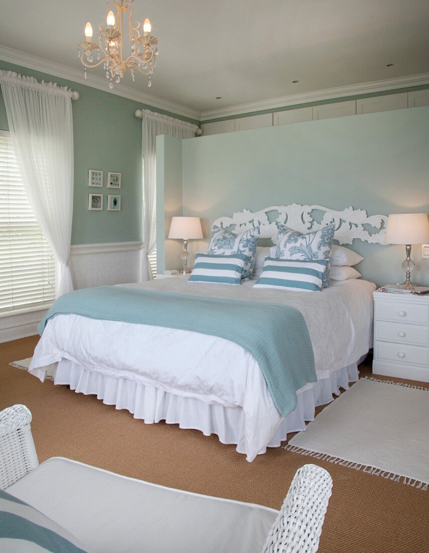 weiße Bettwäsche und pastellblaue Tagesdecke auf Doppelbett mit Trennwand als Bettkopfteil