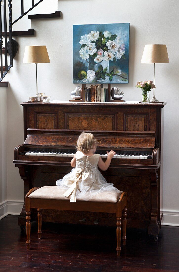 Little girl wearing ruffled dress playing on piano