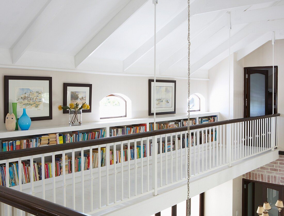 Bücherregal im niedrigen Kniestockbereich eines Galeriegangs