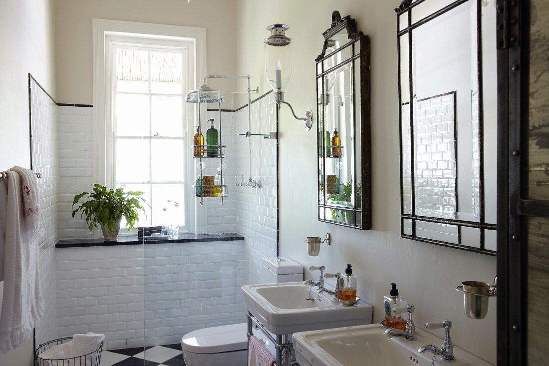 Einzelne Waschtische mit gerahmten Spiegeln an Wand, im Hintergrund Duschbereich vor Fenster mit weissen Wandfliesen
