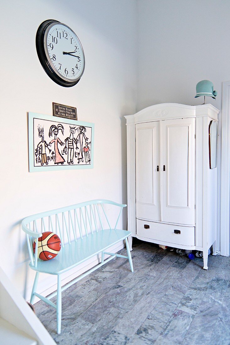 Wooden bench painted pastel blue next to white farmhouse cupboard