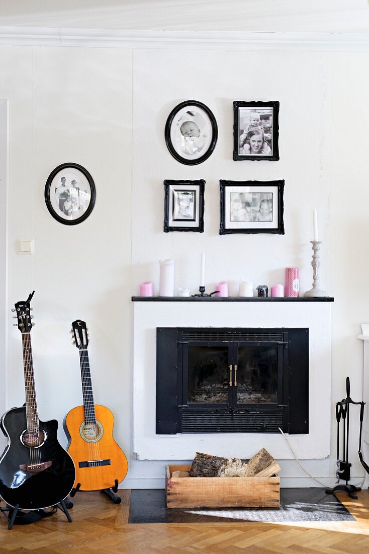 Guitars next to open fireplace below framed family photos