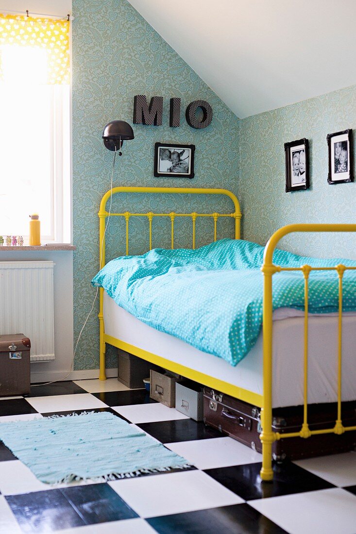 Gelbes Vintage Metallgitterbett auf Schachbrettmusterboden in Jugendzimmerecke im Dachgeschoss