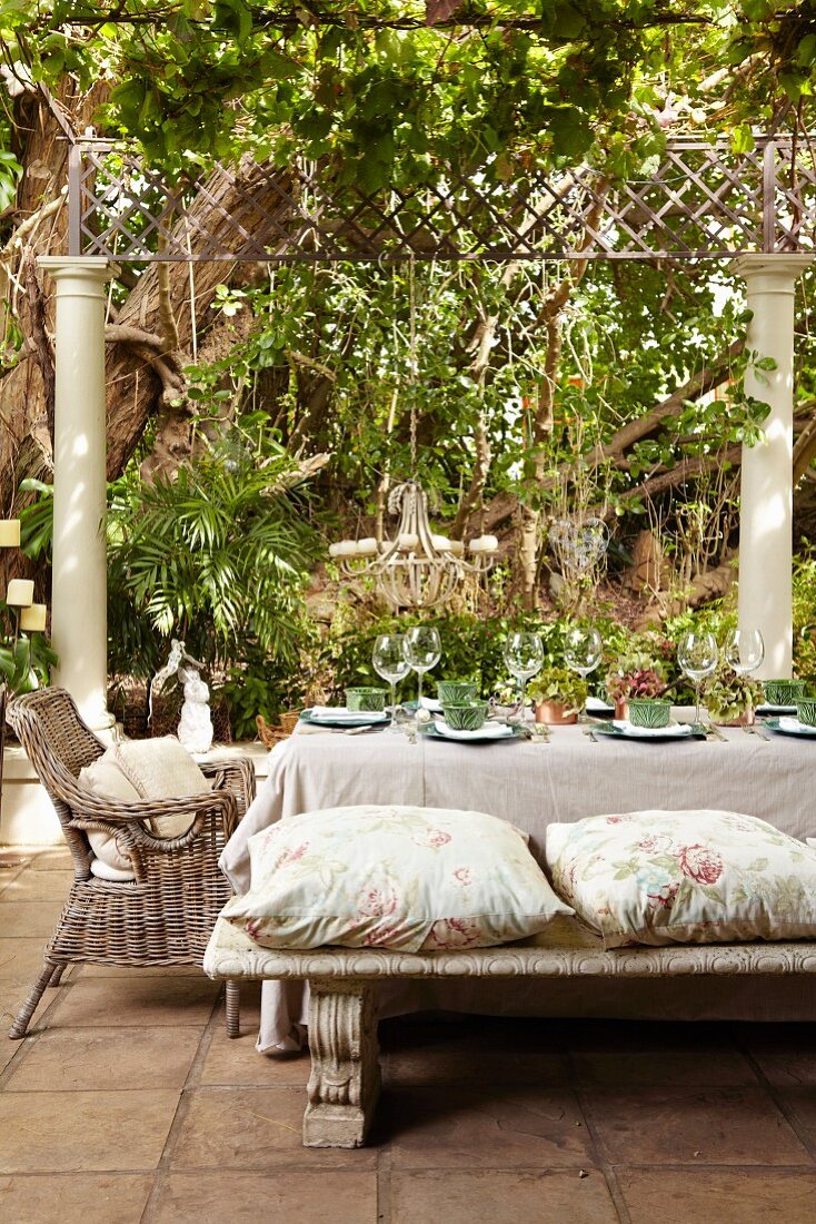 Set table on terrace below climber-covered pergola