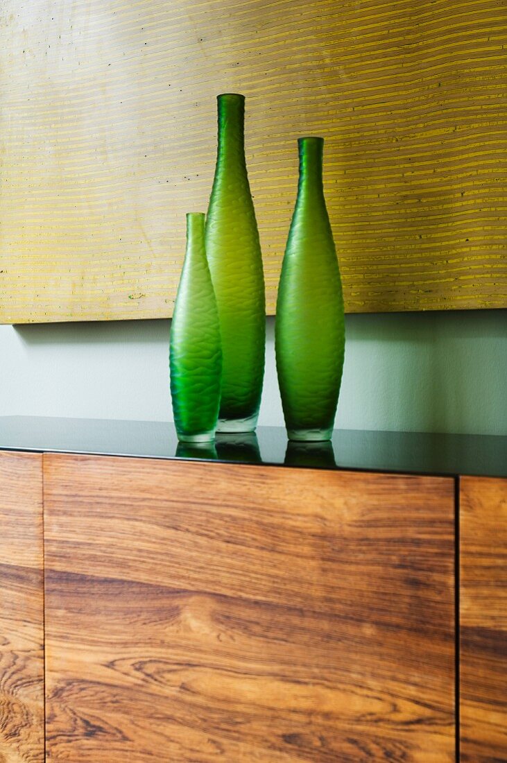 Dreiteiliges Vasen-Set in Grün auf Sideboard mit Front aus Nussbaumholz
