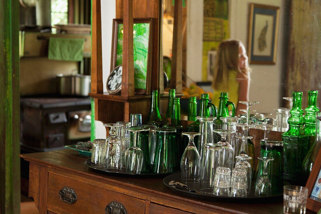 Drinking glasses & glass bottles on antique dressing table with mirror