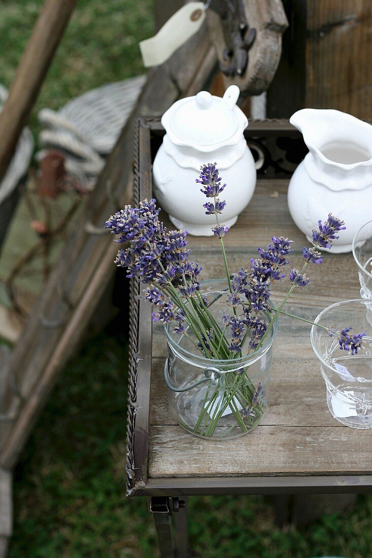 Lavender flowers in glass and china crockery on wooden table