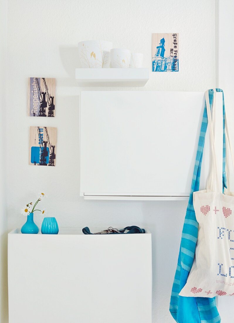Blue Danish vases on white shoe cabinet and artistic postcards on wall