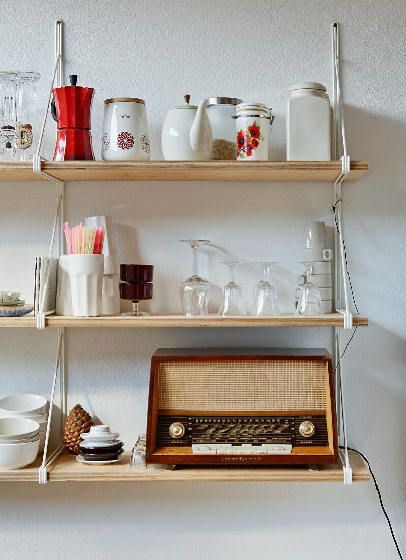 Vintage radio and crocker on wooden bracket shelves mounted on wall