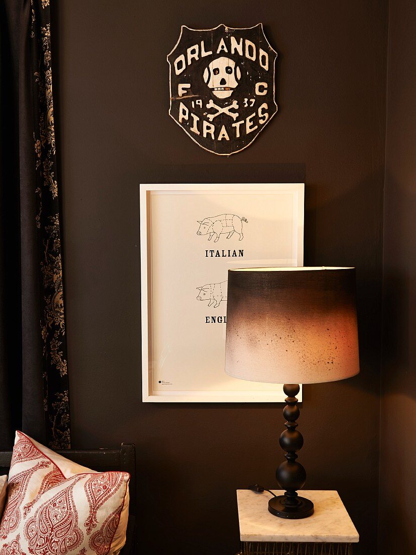 Tischleuchte mit Lampenschirm in Dip-Dye Stil vor dunkelbrauner Wand mit Bildern