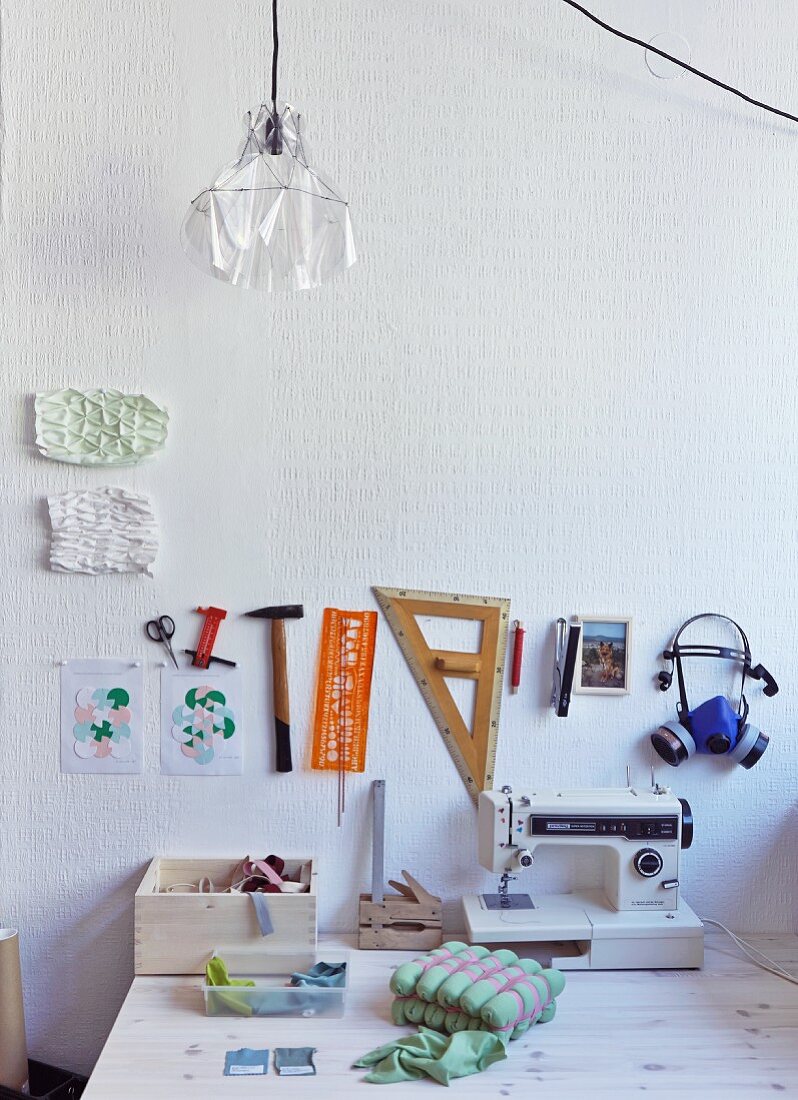 Sewing machine and accessories on desk below drawing utensils, rulers and templates hung on wall