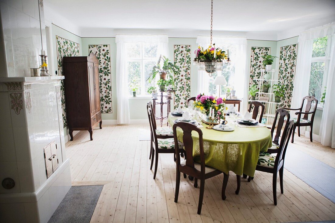 Dining room with dark wooden chairs around table and slim, floral panels on walls in rustic interior
