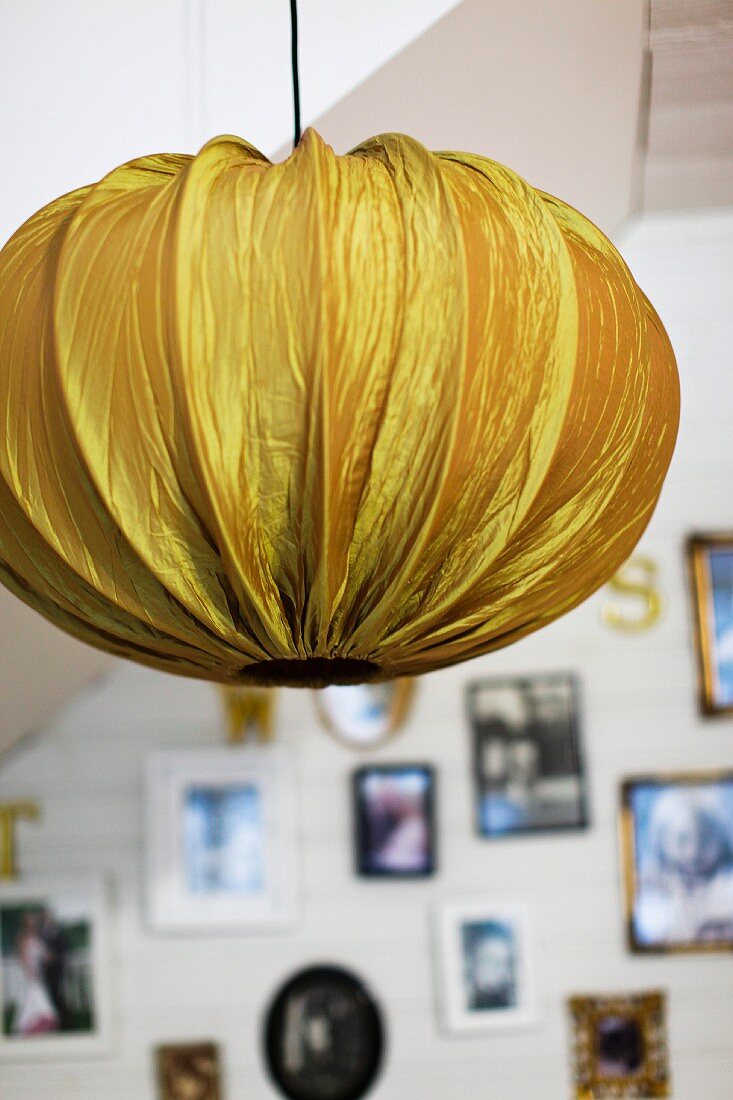 Pendant lamp with gold fabric lampshade; gallery of photos in blurred background