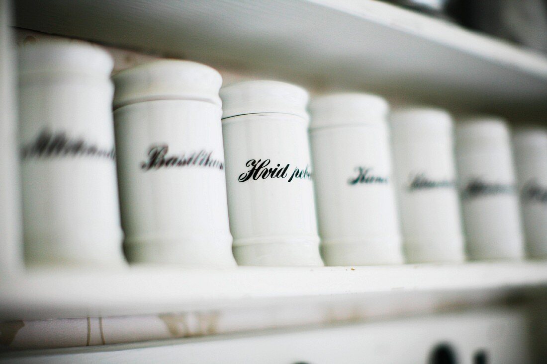 Labelled, white china spice jars on shelf
