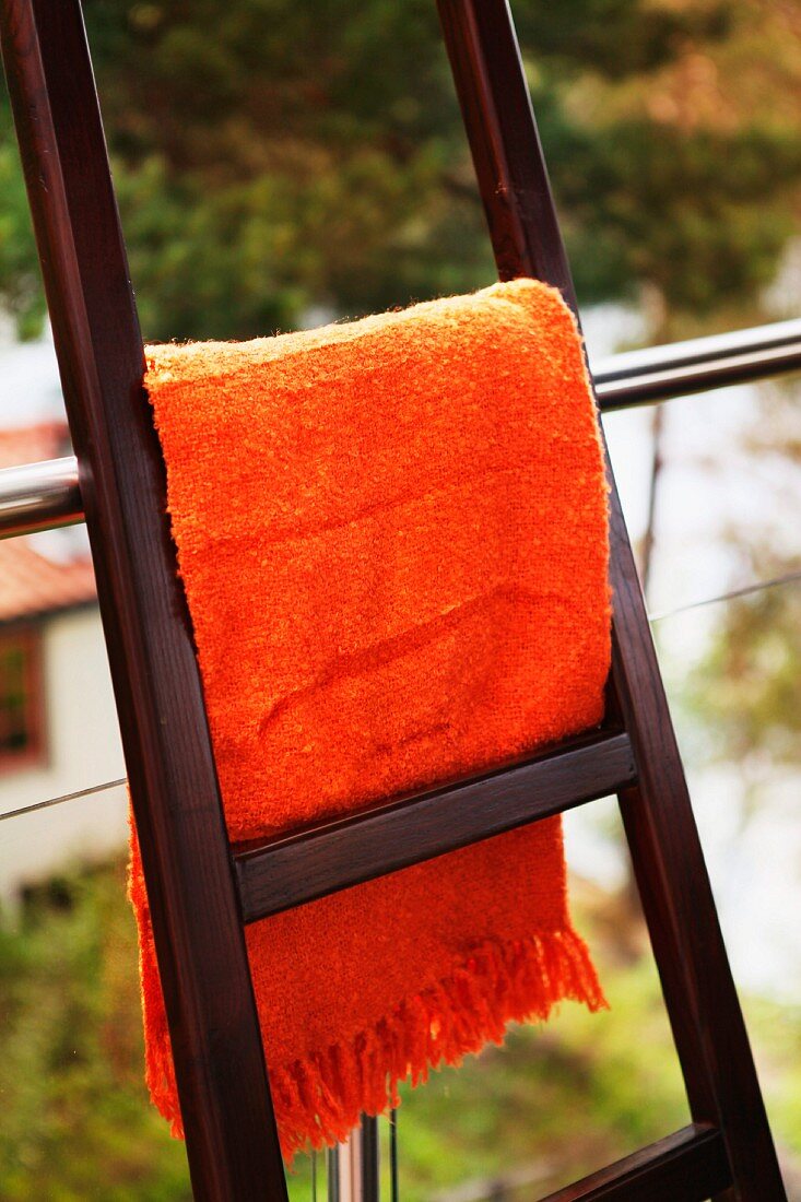 Orange blanket hung over ladder leaning against balustrade