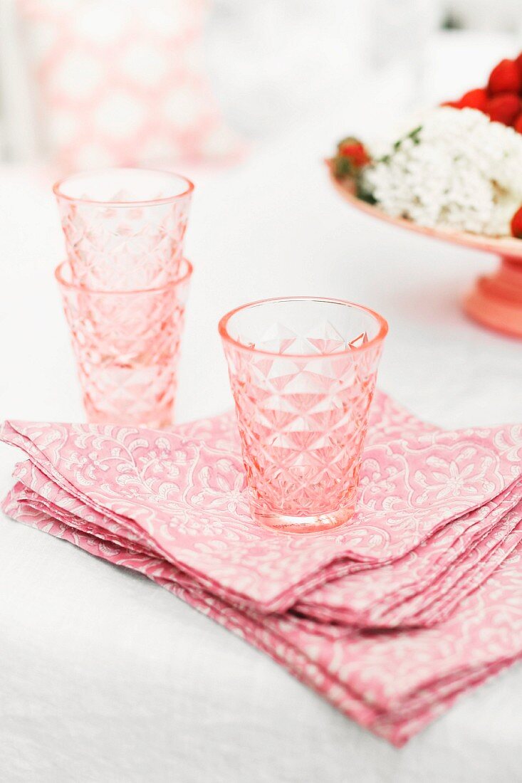 Pink, retro drinking glasses on pink and white patterned, vintage-style linen napkins