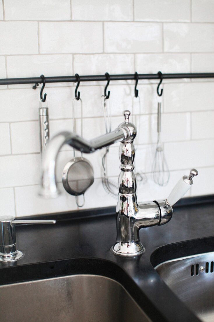 Retro tap fittings on undermount sink and kitchen utensils hanging from metal rail