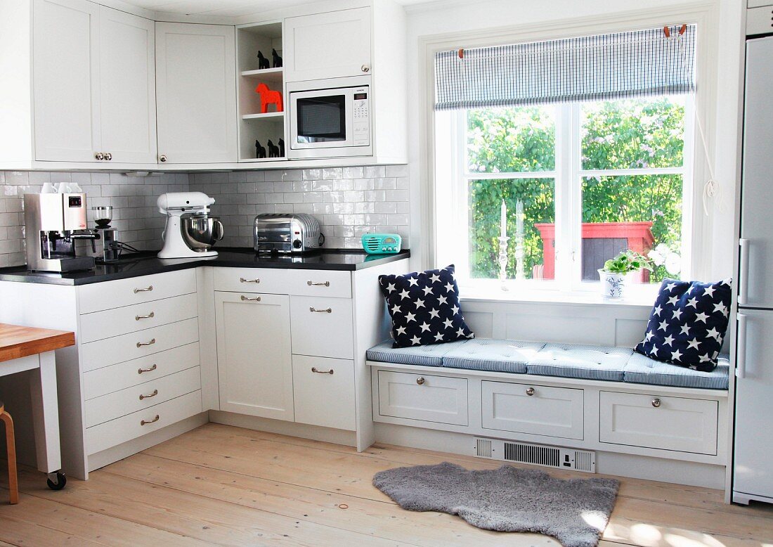 Eckelement einer schwedischen Landhausküche mit blau-weissen Accessoires an integrierter Sitzbank