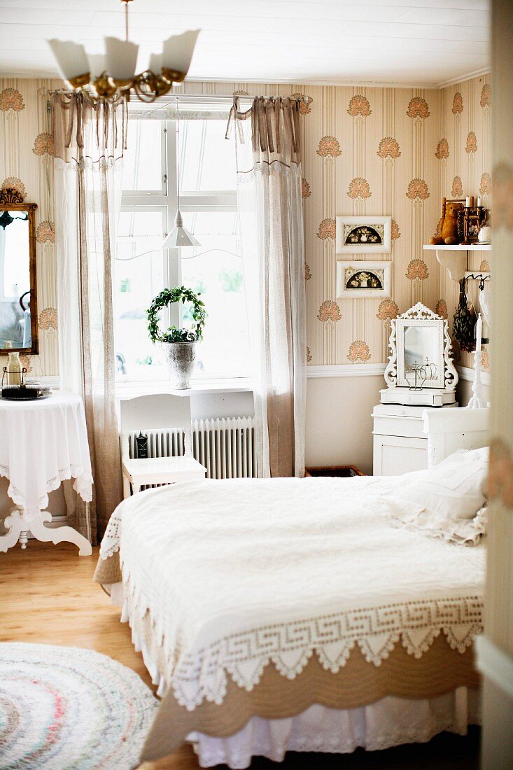 Bett mit weisser Spitzen Tagesdecke in traditionellem Schlafzimmer, mit weissen und beigen Farbtönen