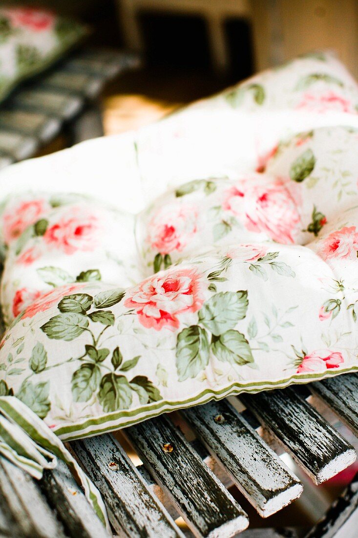 Kissen mit Blumenmuster auf Holzstuhl