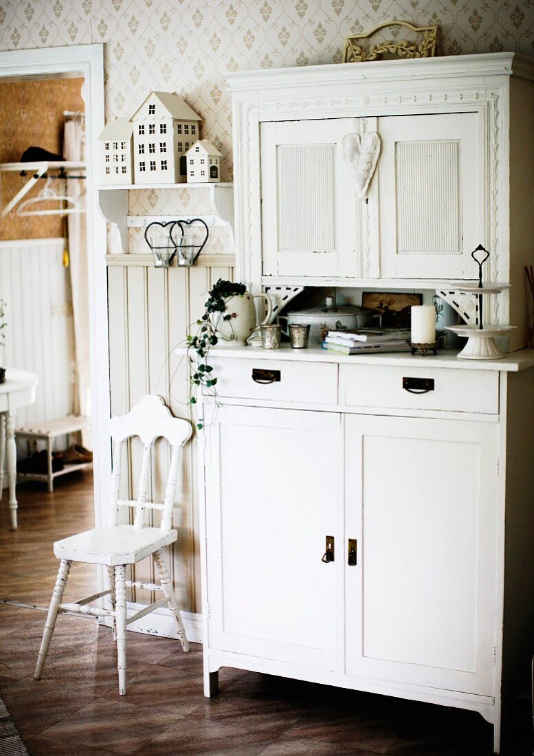 Weiß lackierter Buffetschrank und Stuhl mit geschnitzter Rückenlehne in traditioneller Küche