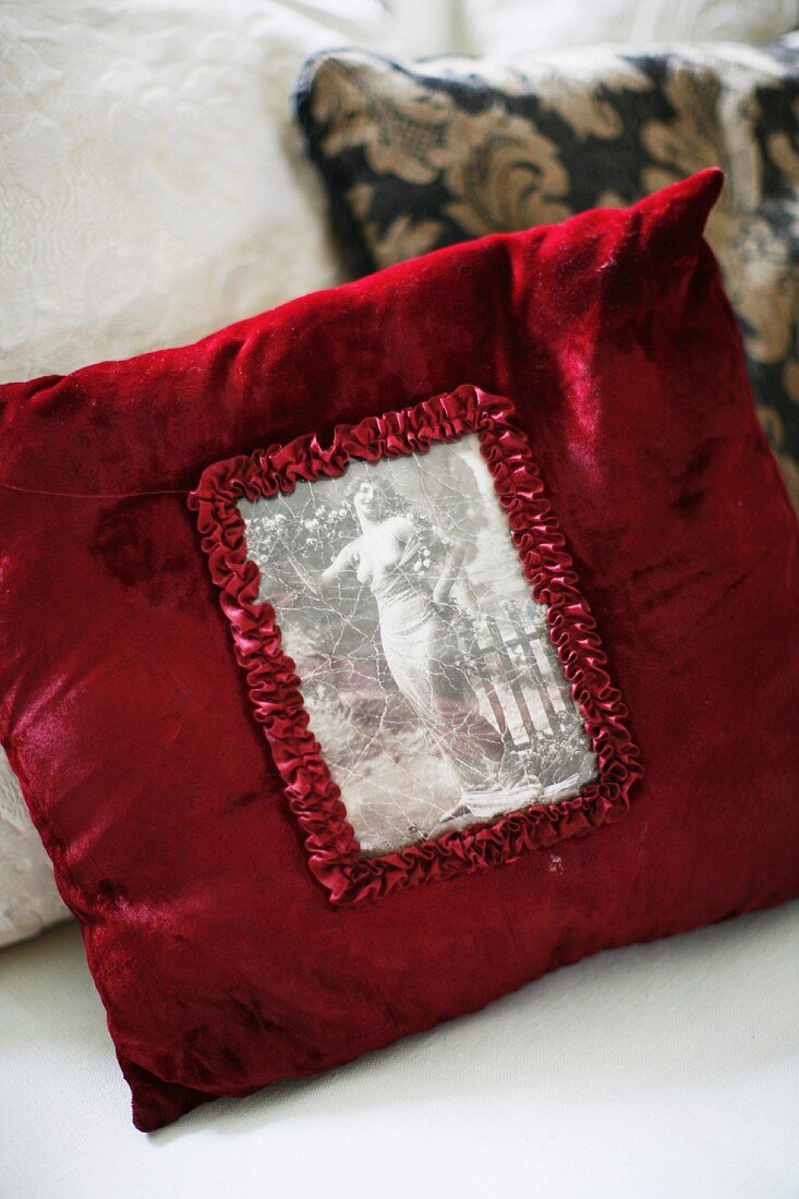 Red velvet cushion with vintage, black and white picture in ruffled edging