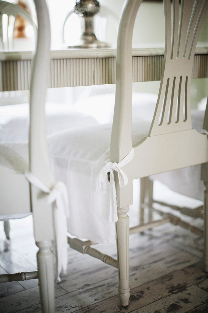 Weiß lackierte Holzstühle mit Schonbezug auf Sitzpolster