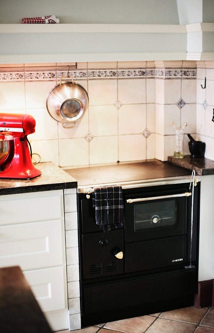 Black, vintage kitchen cooker against white splashback with accent tiles in simple kitchen