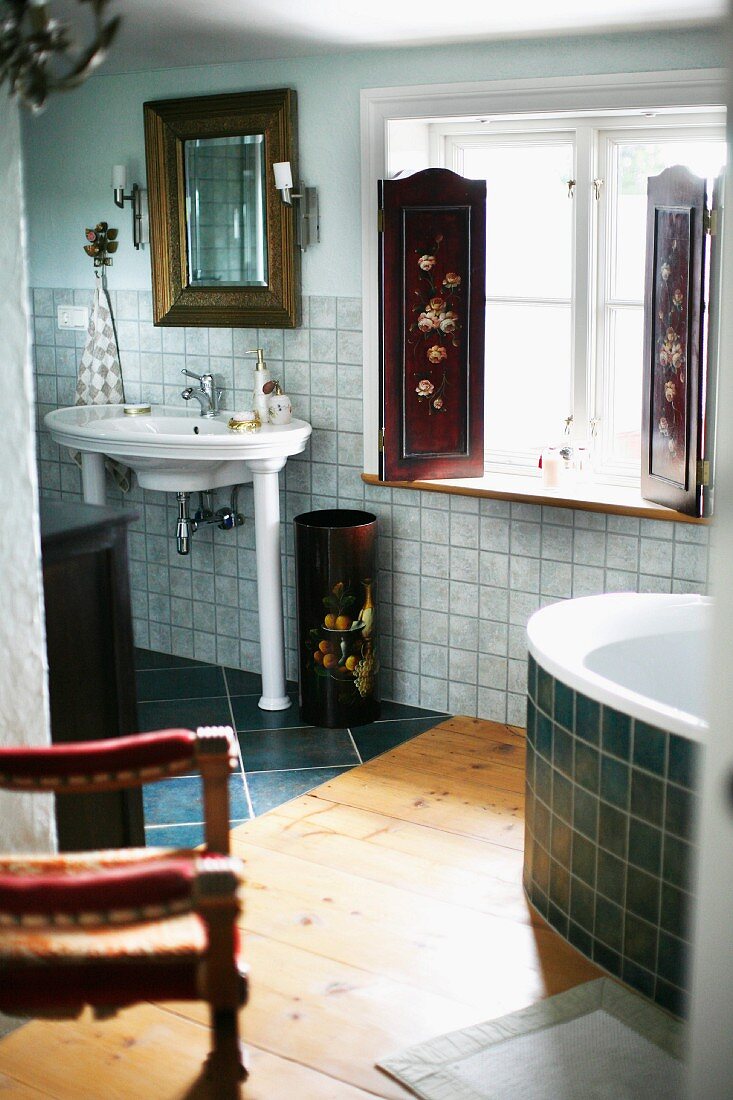 Vintage Standwaschbecken auf Säulen neben Fenster mit bemalten Fensterläden im Bad mit unterschiedlichen Bodenbelägen