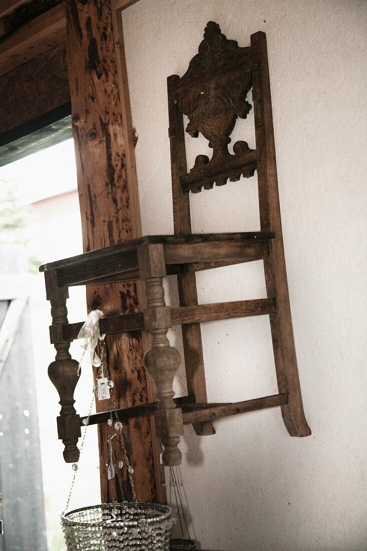 Antiker Küchenstuhl mit Schnitzereien an Wand aufgehängt