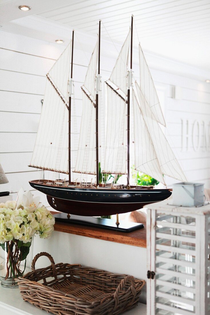 Prächtiges Segelschiff-Modell auf einer Brüstung in skandinavischem Wohnraum; davor Korbtablett und eine Vintage Laterne