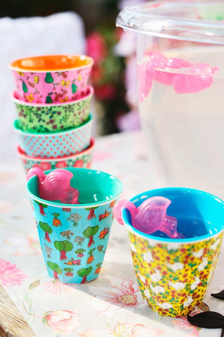Colourful melamine beakers and flamingo-shaped plastic ice cubes for garden party