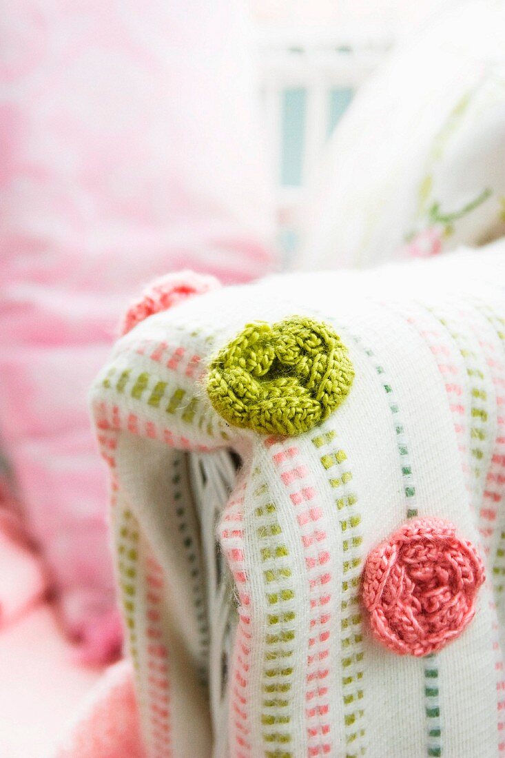 Green and pink crocheted roses on blanket