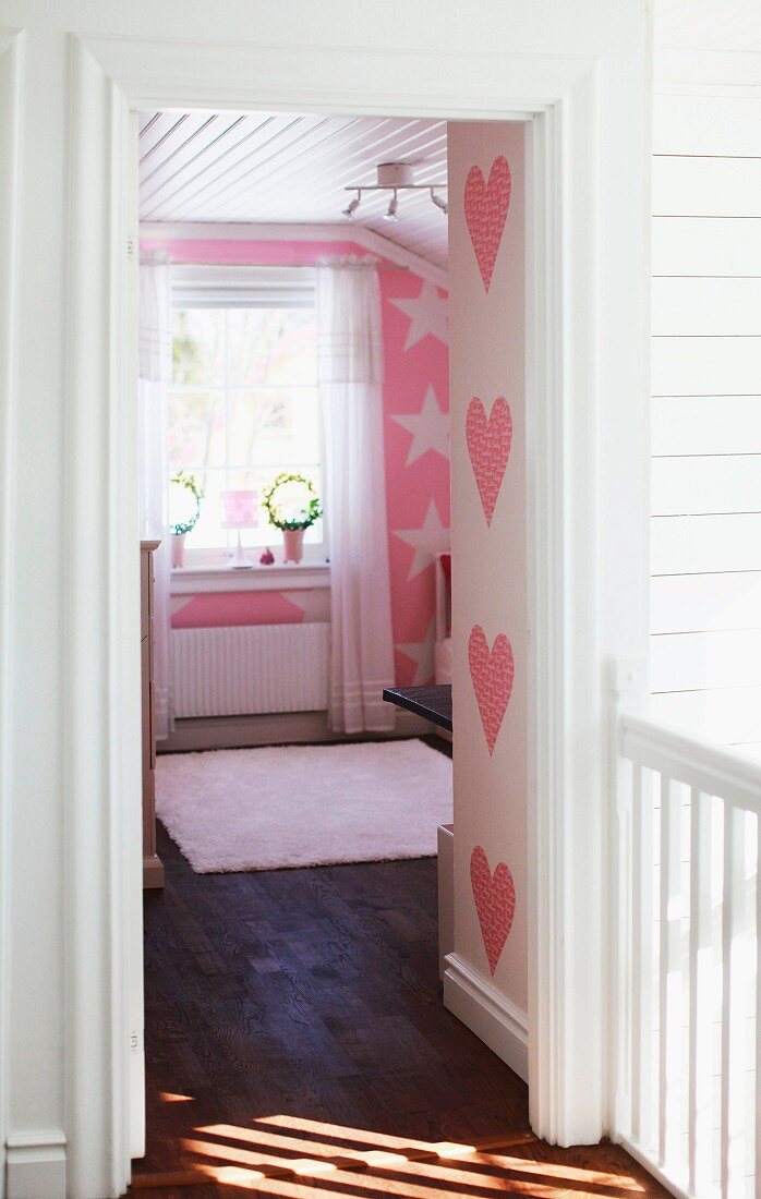 Blick in rosarotes Kinderzimmer mit Herz- und Sternmotiven an den Wänden