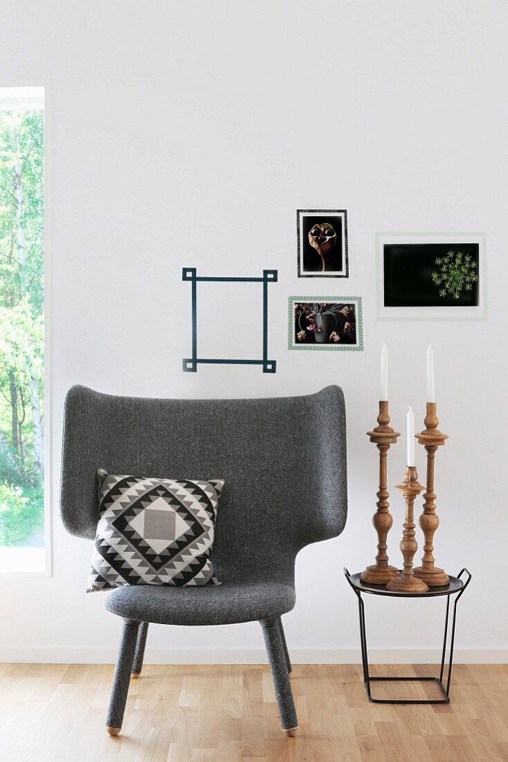 Sessel mit Kissen neben Beistelltisch mit Kerzenhalter-Set, darüber in Masking Tape Bilderrahmen