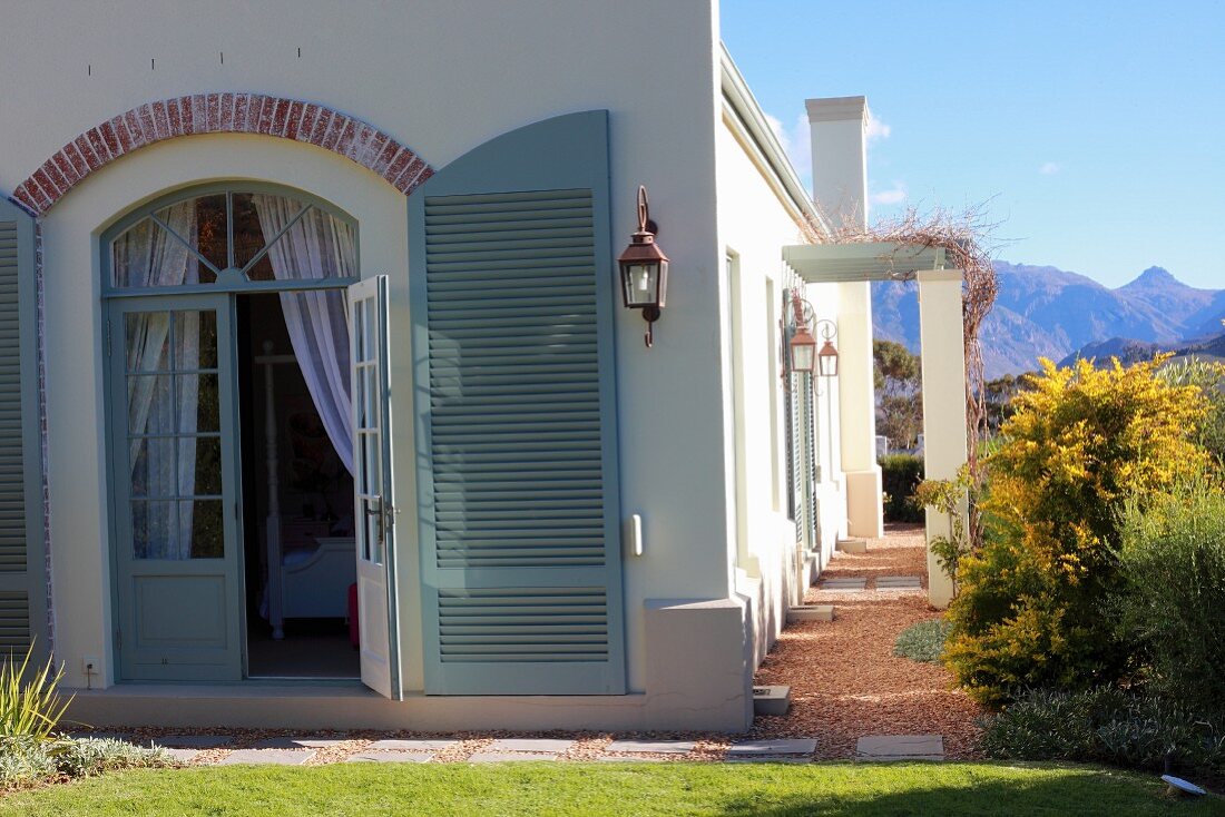 Mediterranes Landhaus mit Rundbogentür und offenem Türladen graugrün lackiert
