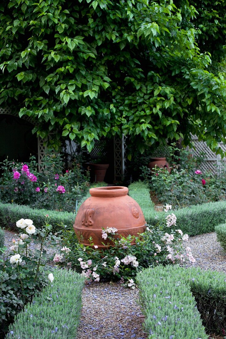 Urn at intersection of gravel paths and flowerbeds edged with low hedges
