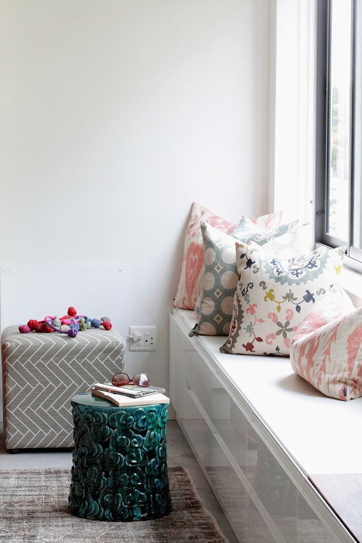 Scatter cushions with various patterns on custom window seat and stool used as side table