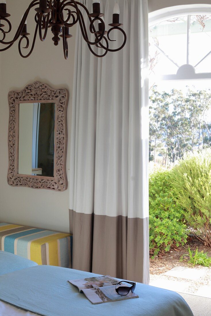 Blick über Bett auf offene Terrassentür mit bodenlangem Vorhang